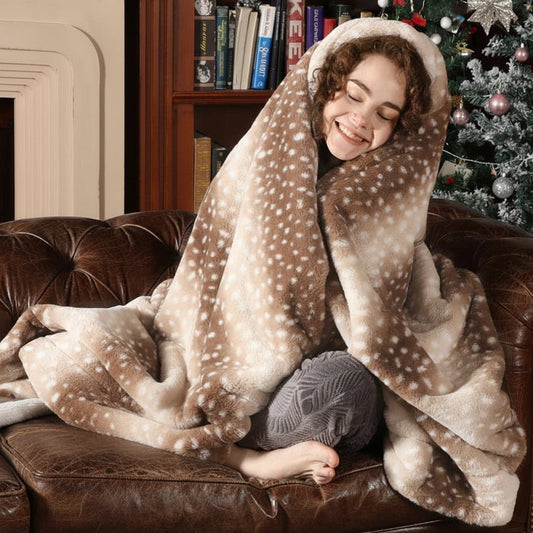 Smiling woman wrapped in the brown spotted fur throw like a hood, sitting cross-legged on a leather sofa. 2