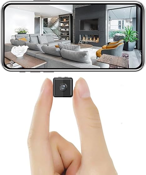 Tiny black cube camera held between two fingertips, with a phone above showing a living room feed 2