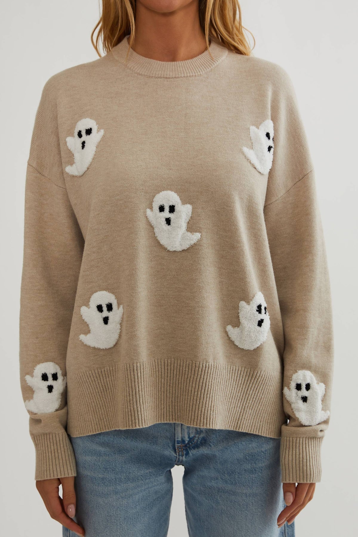 Close-up of the jumper's front, showing textured white ghost appliqués with black faces scattered across the body and sleeves above a ribbed hem. 2