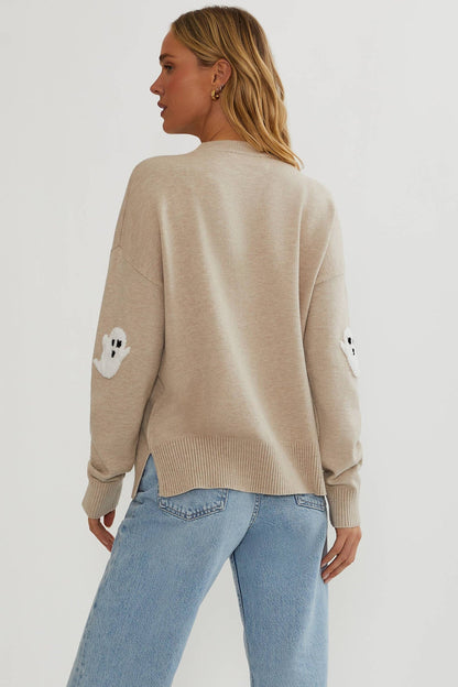 Back view of the plain oatmeal jumper on a model, showing a ghost appliqué on each sleeve and a side slit in the ribbed hem. 5