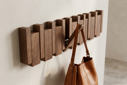 Close-up of dark walnut wall hanger with a tan leather handbag hanging from one folded-out hook 12