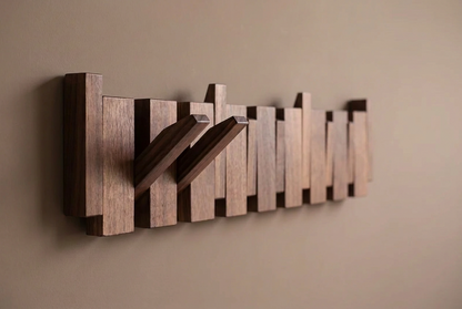 Angled view of a dark walnut rack with two hooks folded out against a taupe wall 12