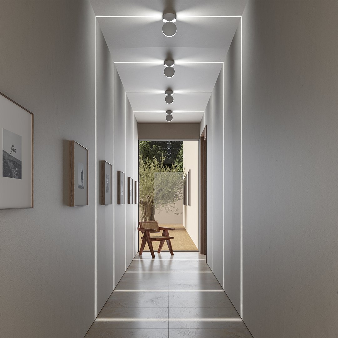 Row of ceiling-mounted round lights in a long hallway, casting thin square outlines of light along walls, ceiling and floor. 1