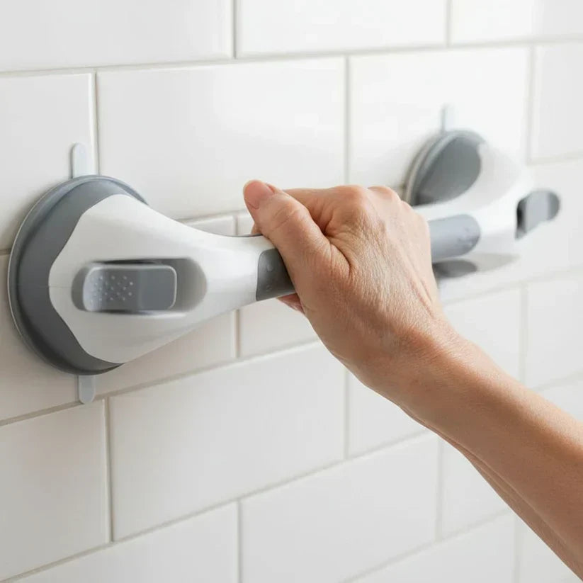 Close-up of a hand gripping the grab bar, showing its two round grey suction bases and locking levers on white tiles. 2