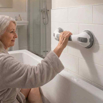 Smiling older woman in a grey robe sits in a bathtub and holds the grab bar mounted on white tiles. 8