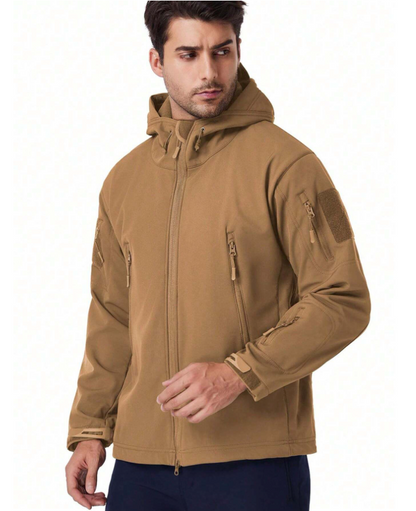 Man wearing the tan hooded jacket, front three-quarter view, showing zipped chest pockets and sleeve patch panel. 16